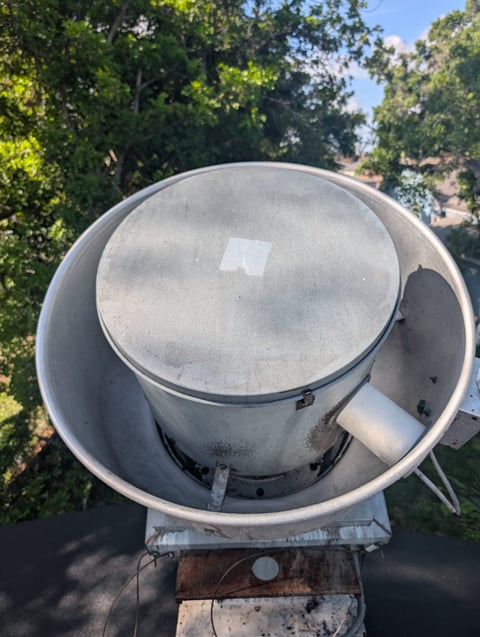 Overhead view of a concrete mixer drum mounted on equipment surrounded by green trees and blue sky